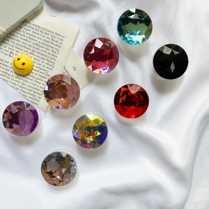 Flat lay of eight colorful faceted gemstone phone socket grips on white fabric background