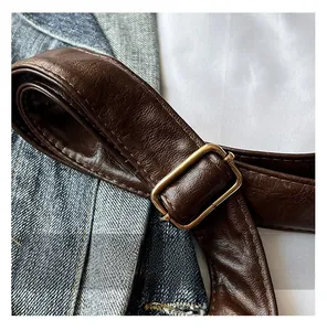 Gros plan d'une bandoulière en cuir marron avec boucle dorée et coutures détaillées