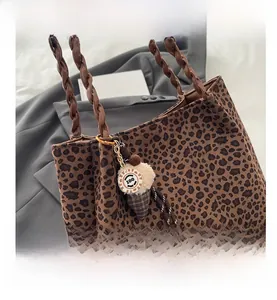 Dettaglio della borsa tote leopardata con manico intrecciato e ciondolo a gelato morbido