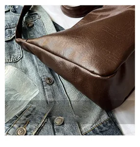 Détail du sac à bandoulière marron foncé avec coutures soignées et texture cuir grainé