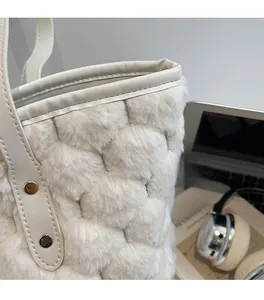 Detail of plush quilted cream handbag with faux fur texture and rivet leather handle