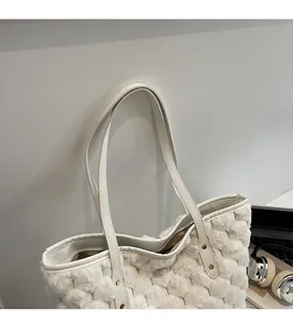 Detail view of white plush tote bag featuring woven texture and leather shoulder strap