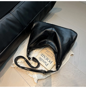 Détail du sac Hobo noir en cuir souple avec bandoulière réglable sur tissu texturé
