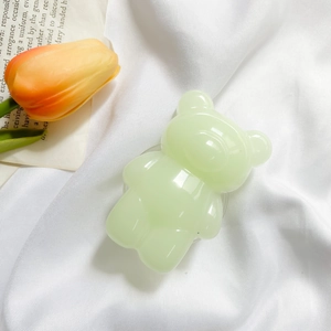 Detailed view of a light green bear-shaped phone grip with a glossy jelly texture finish