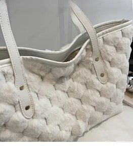 Detail showing the white plush fabric texture and golden rivet reinforcement on the bag