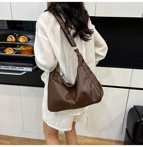 Grand sac hobo marron foncé porté à l'épaule montrant sa taille et son drapé
