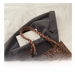 Detailed macro view of woven brown leather handles on a leopard print tote bag