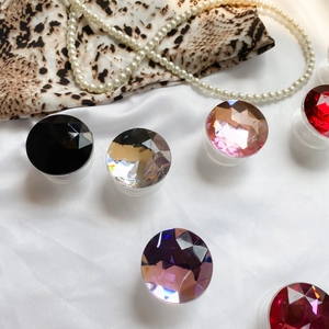 Macro shot of colorful gemstone folding phone grips on silk fabric with pearl necklace