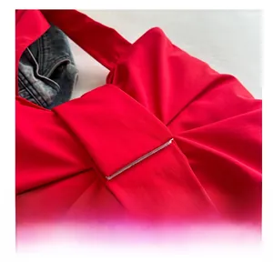 Dettaglio della borsa in tessuto rosso con nodi a fiocco e texture plissettata