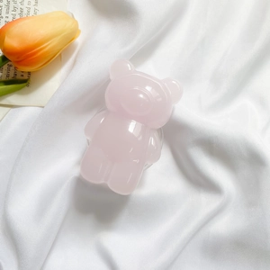 Close-up of a pink 3D gummy bear phone socket on soft white fabric background