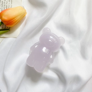 Detail shot of a lavender translucent 3D bear phone grip on elegant white silk fabric
