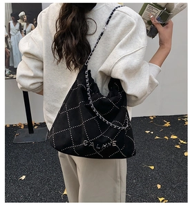 Detail of black quilted suede bucket bag with silver studs and chain strap on model