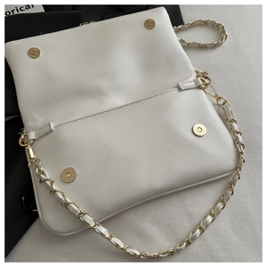 Detailed view of white litchi pattern leather bag with gold magnetic snaps and chain strap