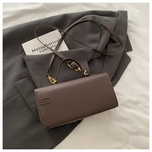Detail view of deep brown structural shoulder bag with gold hardware on gray blazer