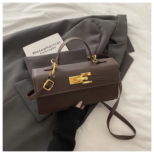 Detail of dark brown litchi grain bag featuring a vintage golden twist lock on a grey suit