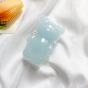 Close-up of a light blue 3D bear popsocket on soft white fabric background