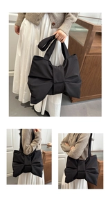 Detail view of large bow design on black nylon shoulder bag with wide strap