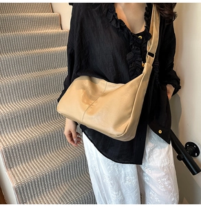 Sac hobo en similicuir beige porté par un mannequin avec large bandoulière et fermeture