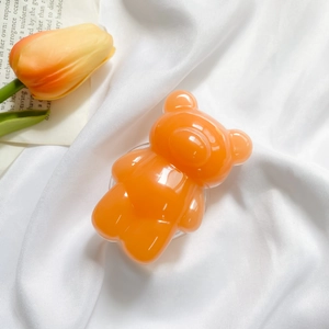 Macro detail of glossy orange gummy bear phone grip on textured white background fabric