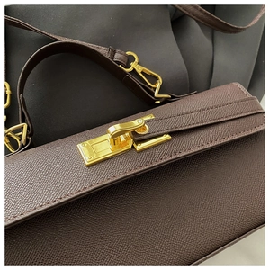 Detailed close-up of golden metal twist lock on coffee brown Epsom leather handbag