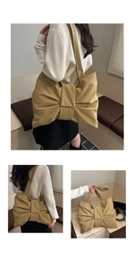 Detail of soft earth-tone tote bag featuring a large bow design and wide shoulder strap