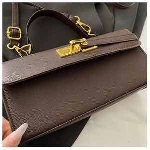Detail of dark brown lychee texture leather handbag with gold metal twist lock buckle