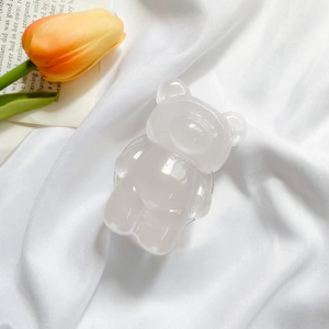 Detail of cute milky white resin bear phone socket on elegant white silk background
