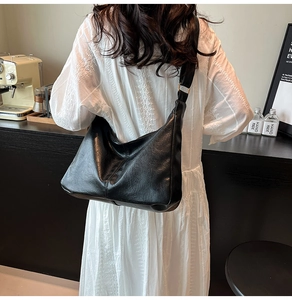 Détail du grand sac bandoulière noir avec texture plissée sur un mannequin décontracté