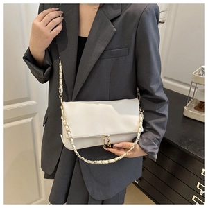 Detailed view of white crossbody bag featuring textured lychee leather and gold chain strap