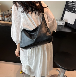 Détail du grand sac hobo noir en similicuir brillant porté par un mannequin