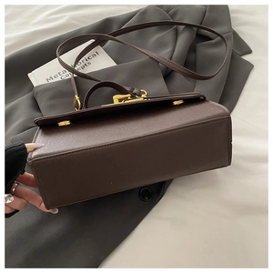 Close-up of dark brown lychee pattern leather handbag with golden metal twist lock and stitching