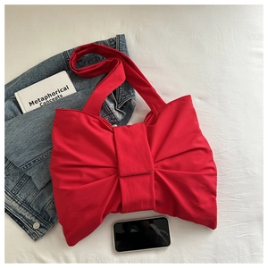 Top view of a bright red oversized bow shoulder bag on a clean lifestyle background
