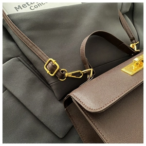Detail of dark brown cross-grain leather bag featuring gold twist-lock and adjustable strap