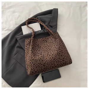 Detail of leopard print tote bag with brown woven handles and spacious interior design