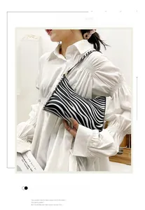 Detail of zebra pattern baguette shoulder bag styled with a white pleated shirt