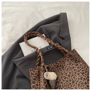 Detail of leopard print tote bag with woven brown strap and plush ice cream charm