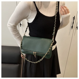Close-up of dark green lychee textured crossbody bag with metal zipper and gold chain