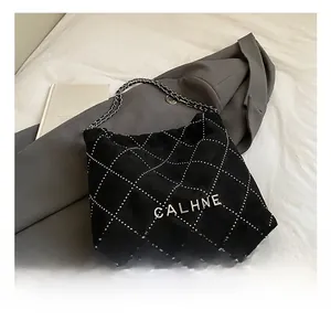 Detail view of black suede bucket bag with quilted white dots and silver chain strap