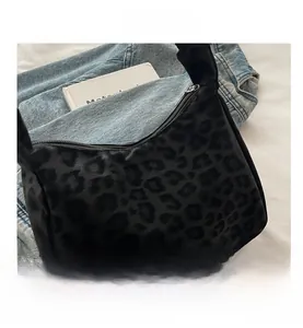 Macro detail of black leopard pattern jacquard fabric and metal zipper on hobo bag