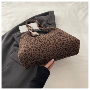 Detailed close-up of leopard print tote bag with woven handles and fluffy charm ornament