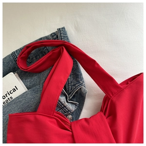Detail of red fabric shoulder bag featuring smooth zipper and premium stitching texture