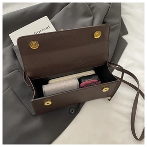 Detail of dark brown pebble leather bag with dual gold magnetic clasps and interior space
