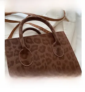 Close-up of leopard print handbag with plush texture, round handles and slim strap