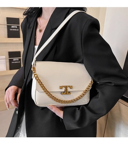 Detail of off-white leather bag featuring gold T-shaped metal buckle and chunky chain strap
