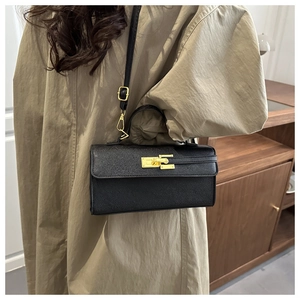 Detail of a black leather crossbody bag with golden clasp and structured handle