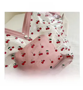 Close-up of cherry print transparent PVC tote bag with pink leather edges and metal buckles