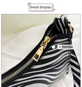 Detailed close-up of golden metal zipper and zebra print texture on cowhide baguette bag