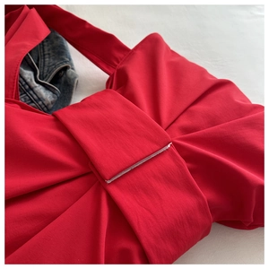 Close-up of the red ribbon bow design on a stylish matte shoulder bag with fine stitching