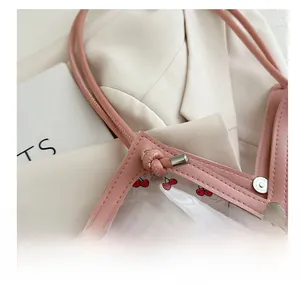 Close-up of pink cherry print tote bag showing PVC texture and metal rivet details
