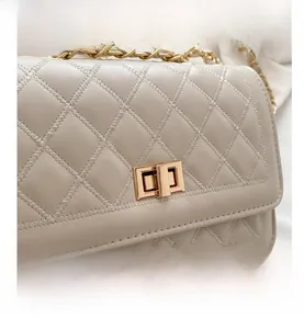 Close-up of beige quilted bag showing Z-shaped stitching and golden metal clasp